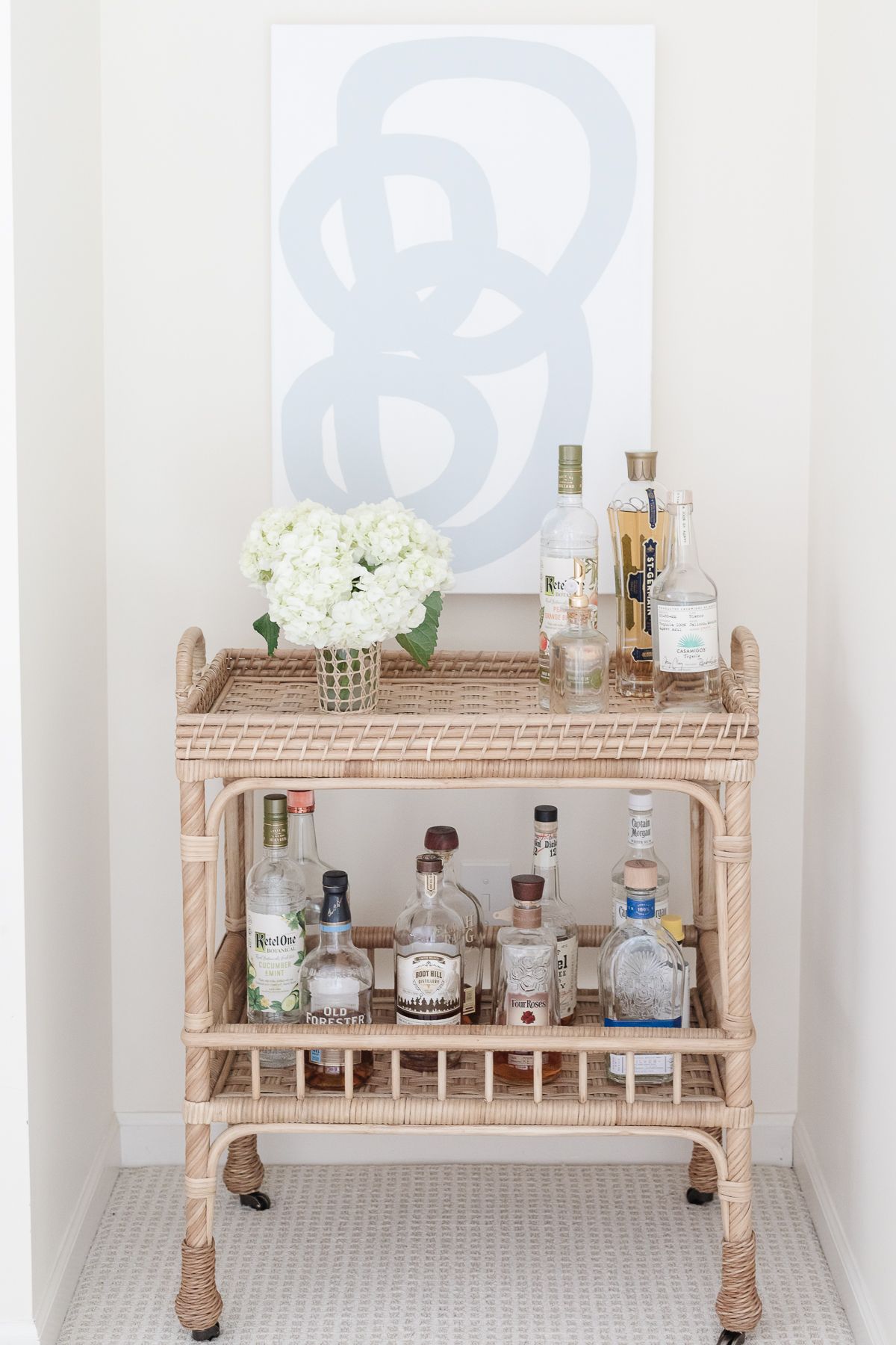 A rattan bar cart with a vase of white hydrangea