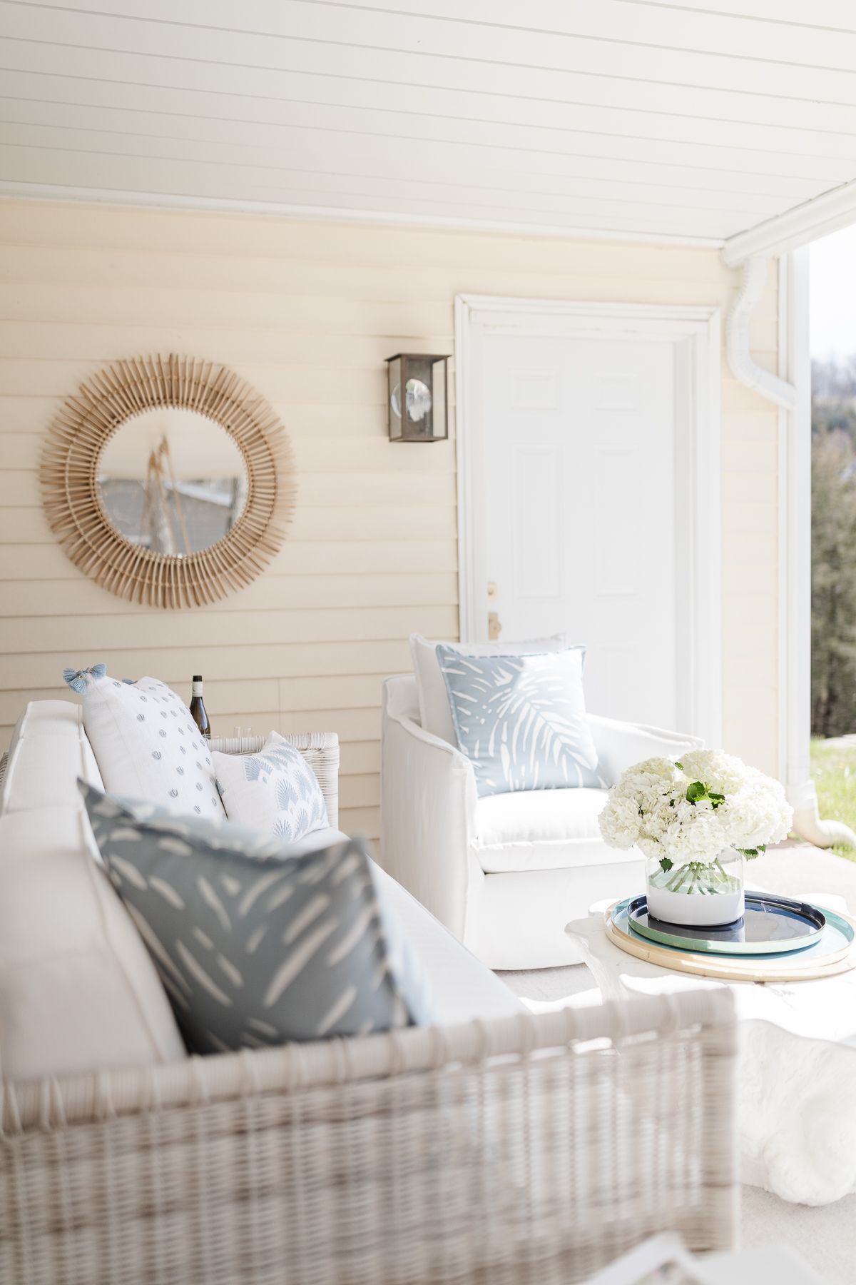 An outdoor patio with a white sofa and a rattan mirror