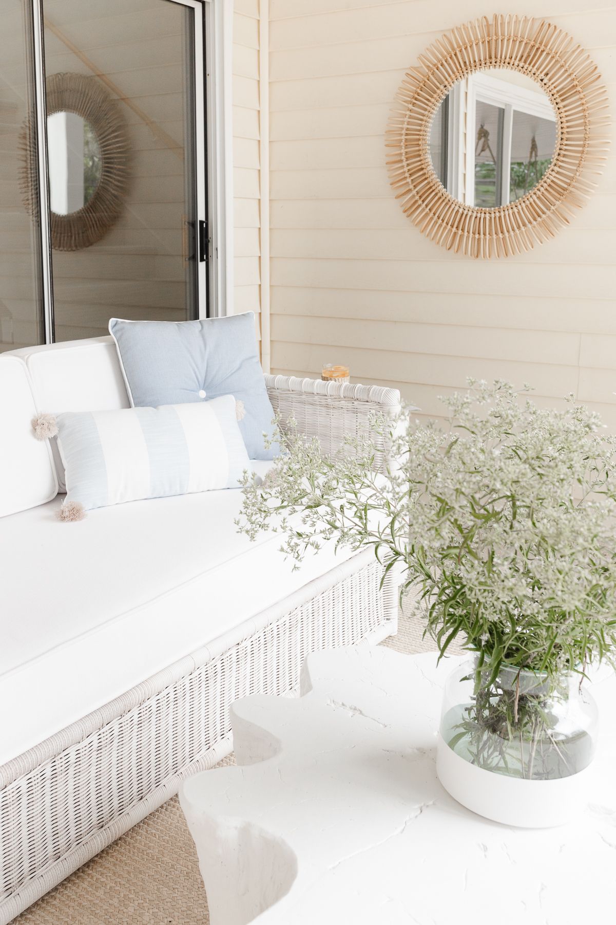 An outdoor patio with a white sofa and a rattan mirror