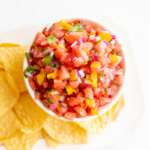 Bowl of fresh tomato salsa recipes with colorful diced vegetables, accompanied by tortilla chips.