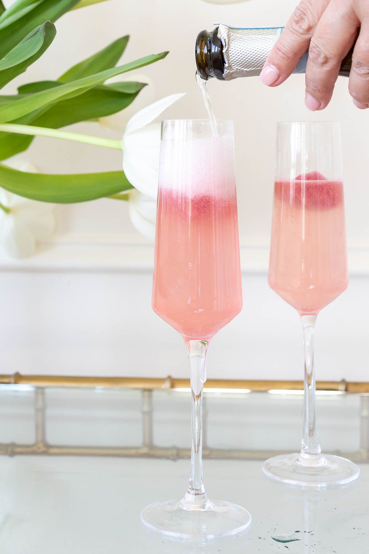 Champagne pouring into two glasses of sorbet mimosas
