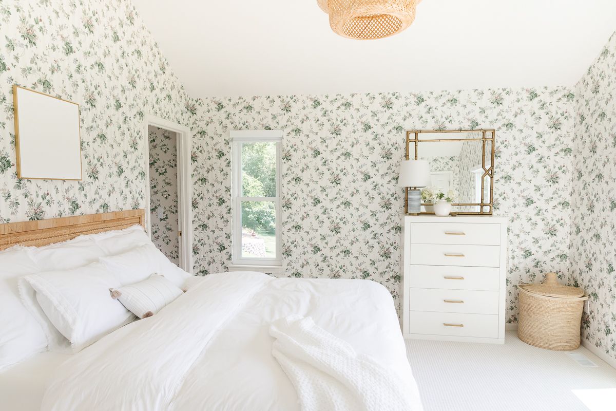 A wallpapered bedroom with plaster canvas art over the bed