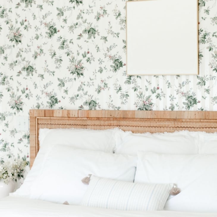 A wallpapered bedroom with white textured wall art over the bed