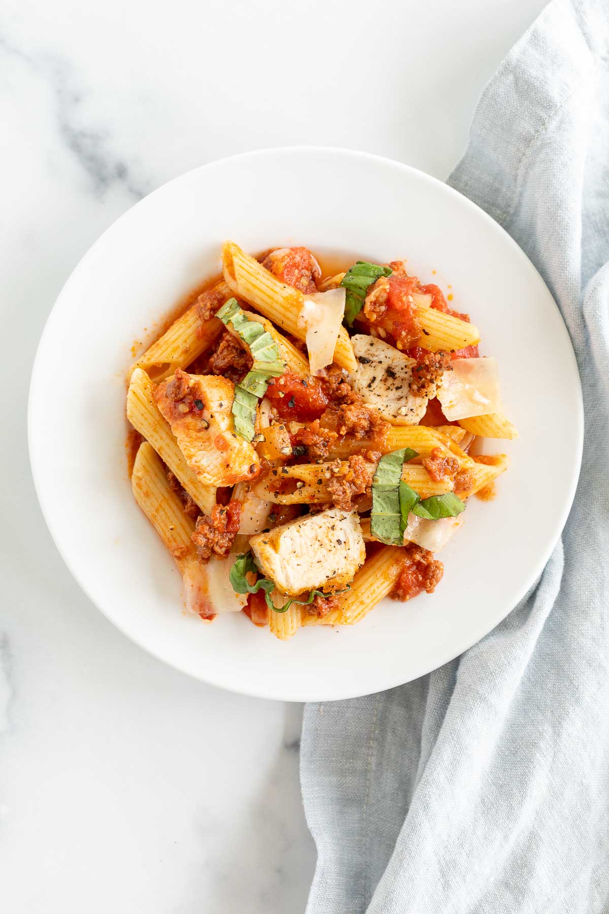 Chorizo and chicken pasta on a white plate.