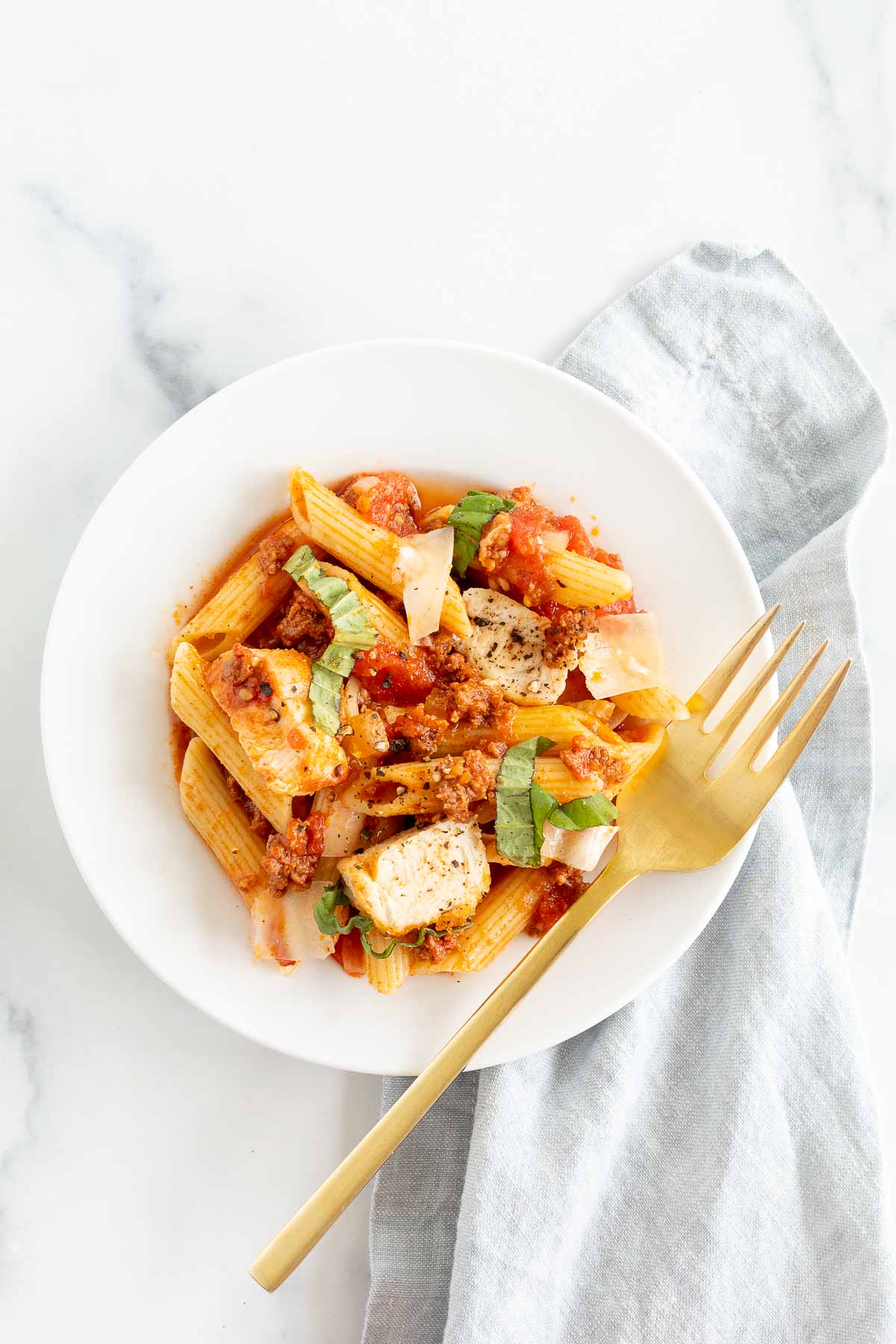 Chorizo and chicken pasta on a white plate.