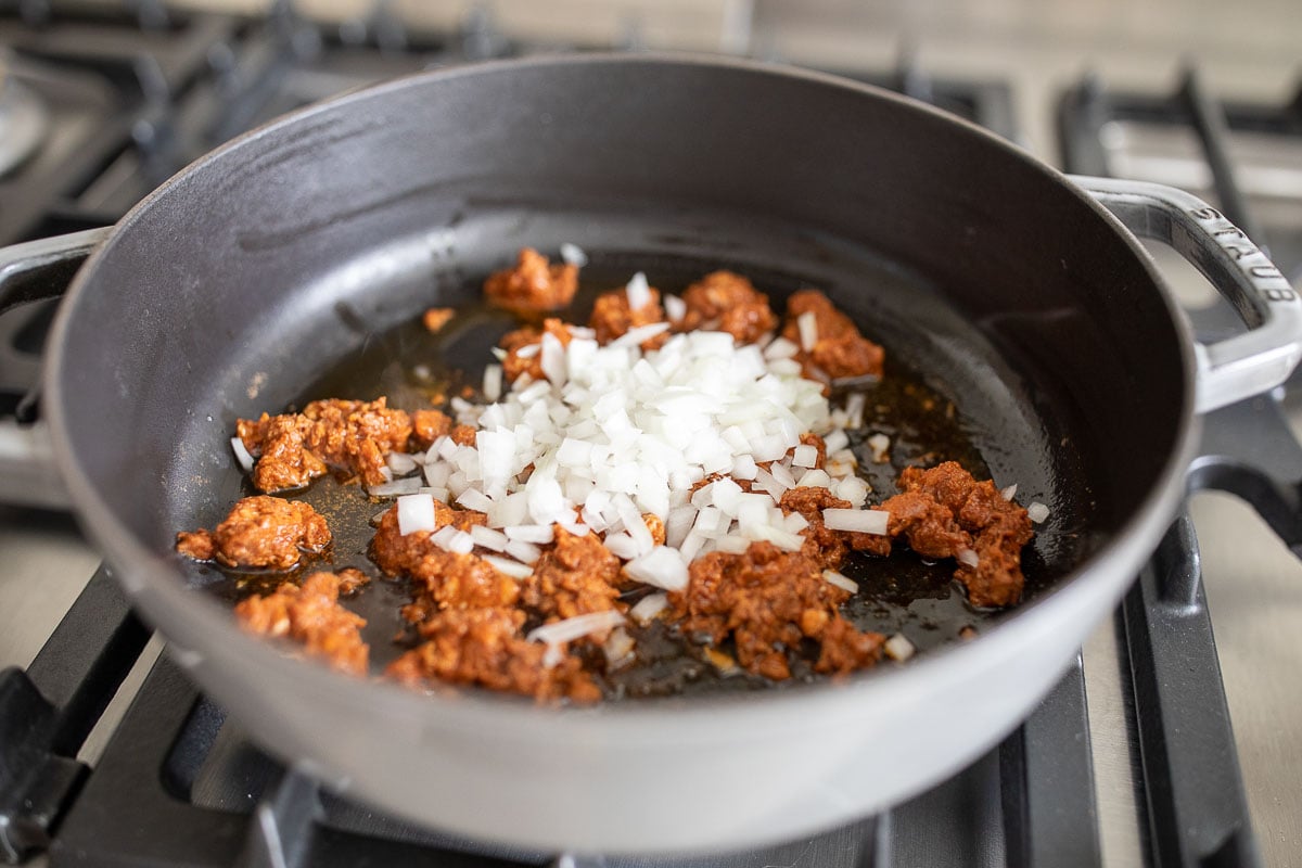 chorizo and onions in a cast iron skillet on a stove top