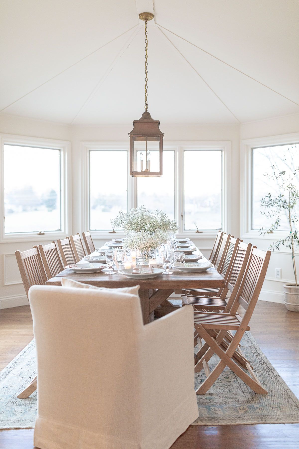 A farmhouse dining table surrounded by wood chairs in a white dining room