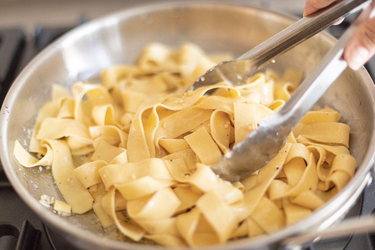 parmesan noodles being tossed in a silver pan