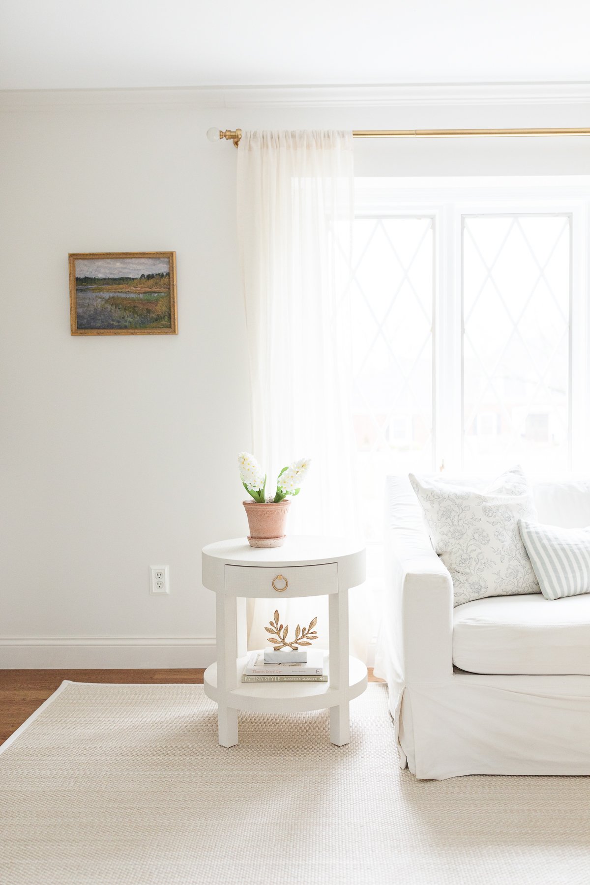 A white living room with white furniture and a soft beige rug.