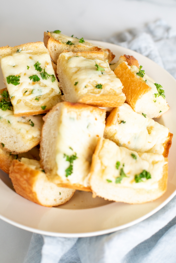 A plate of Italian cheese-topped garlic bread garnished with parsley.