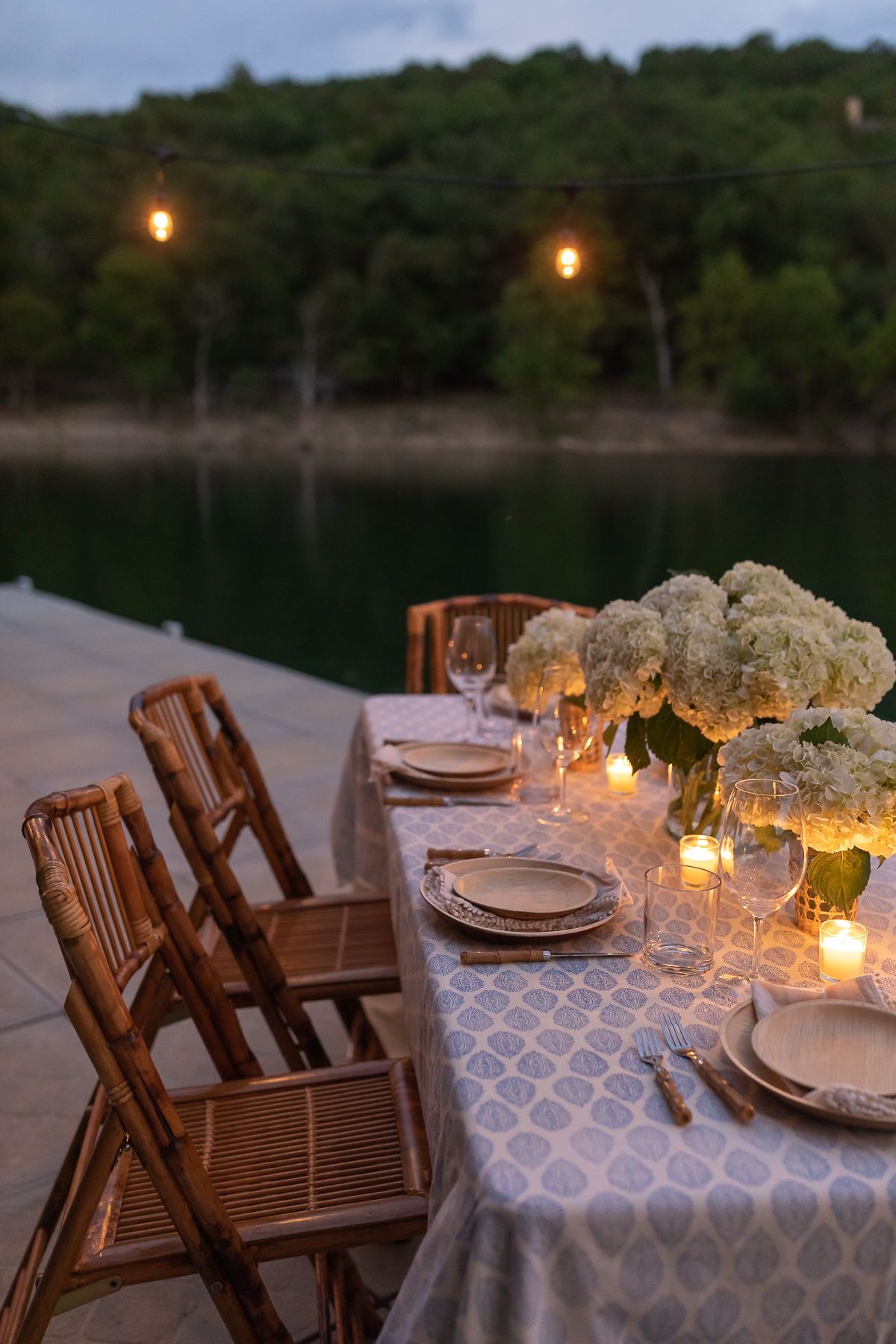 An outdoor dining table set up with string lights above