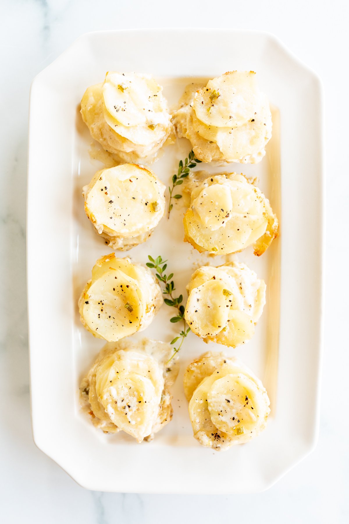Tasty potato side dishes on a white plate with sprigs of thyme.