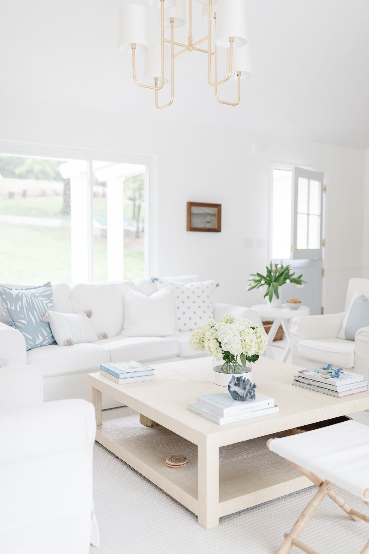 A bright white living room with a white slipcovered sofa and light blue pillows