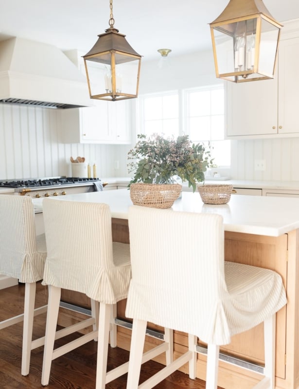 Kitchen island bar stools with striped slipcovers in a white kitchen