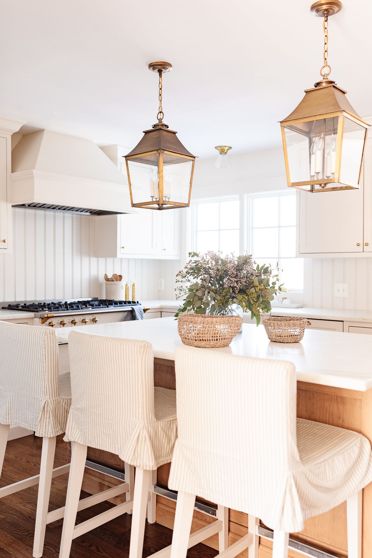 Kitchen island bar stools with striped slipcovers in a white kitchen