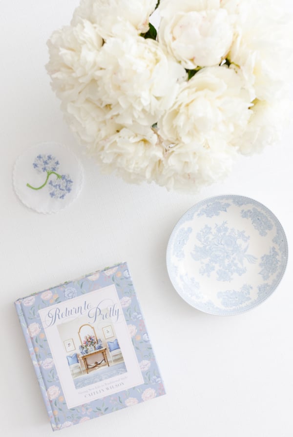 A coffee table featuring white flowers and a blue and white coffee table book.