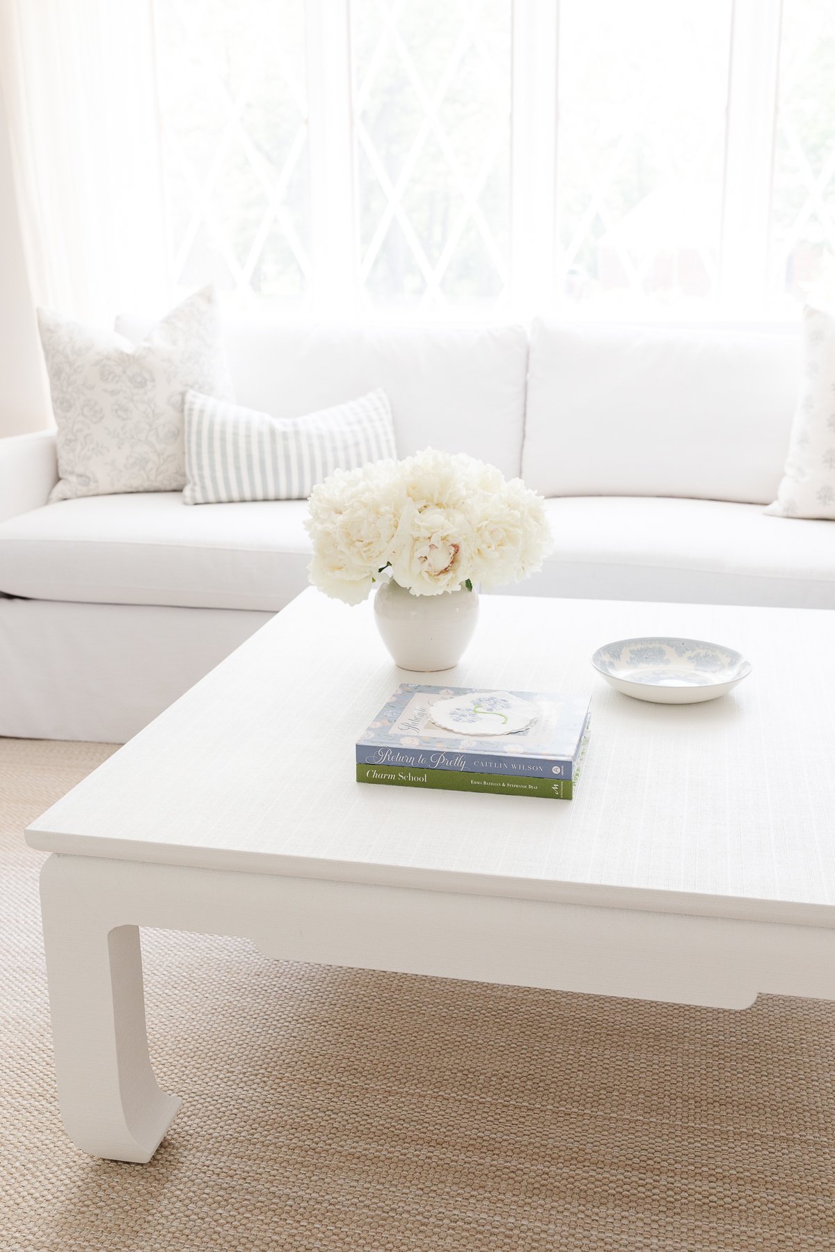 A coffee table featuring white flowers and a blue and white coffee table book.