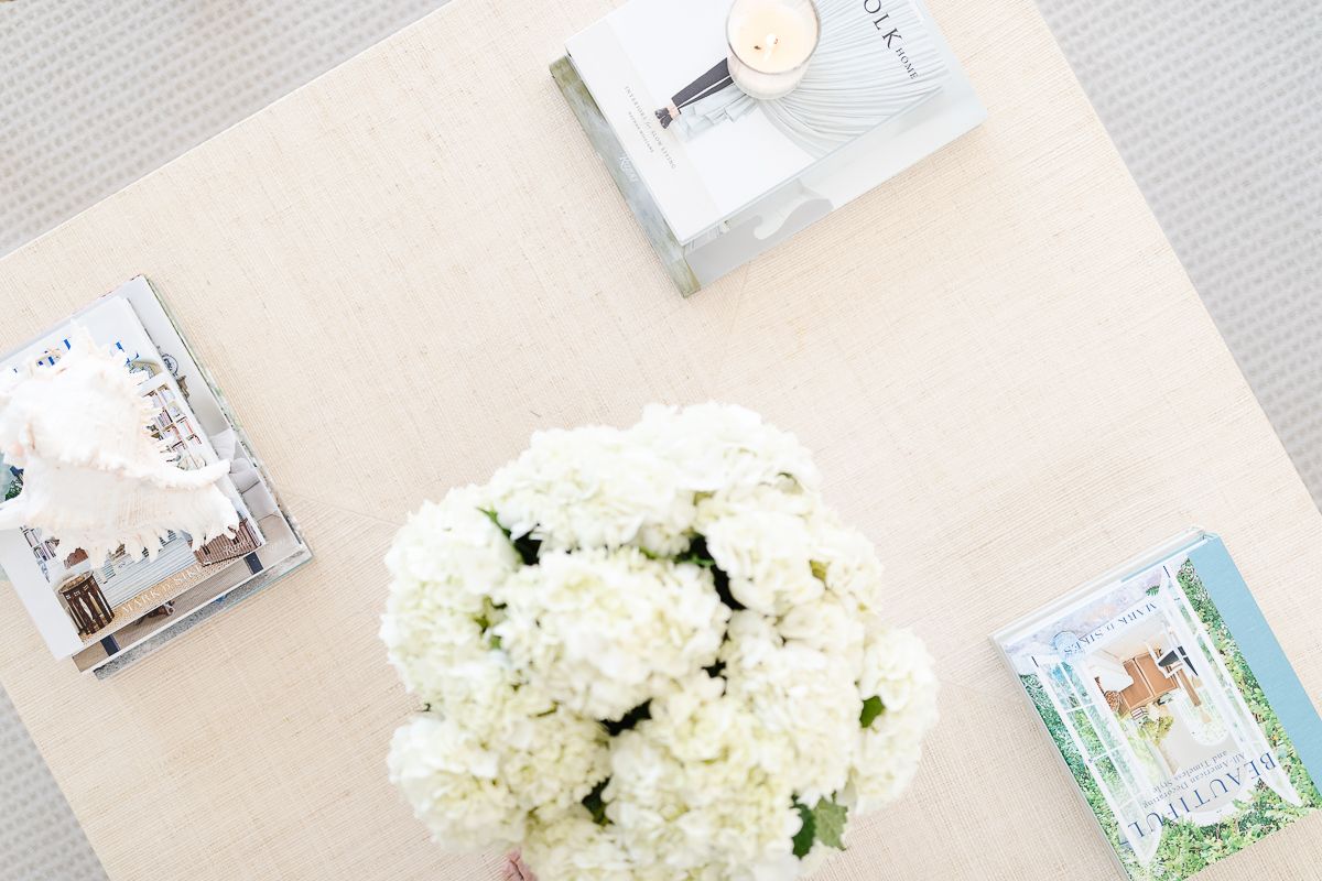 A raffia coffee table decorated with white flowers and books