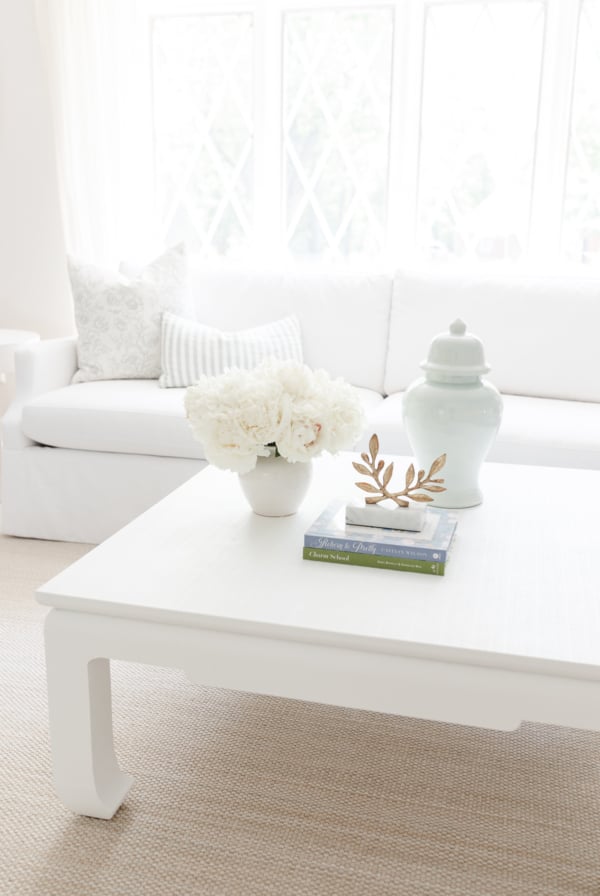 A white coffee table with soft blue and white coffee table decor.