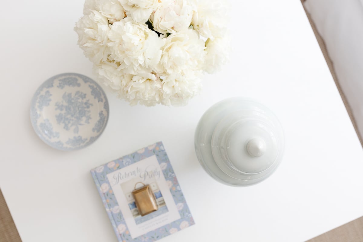 A white coffee table with soft blue and white coffee table decor.