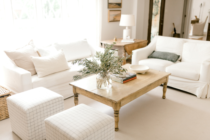 A wood coffee table in a white room with natural, neutral coffee table decor. 