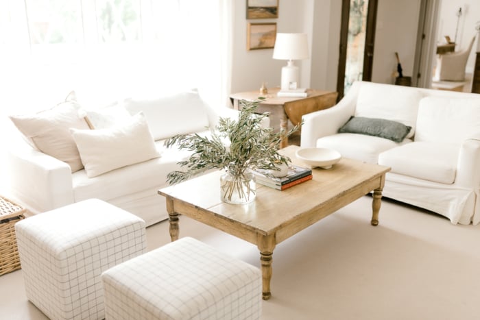 A wooden coffee table in a white room with natural, neutral coffee table decor. 