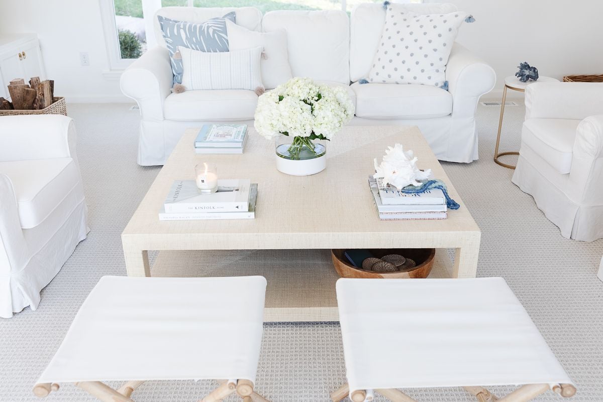 A white living room with coastal accents and blue and white coffee table decor.