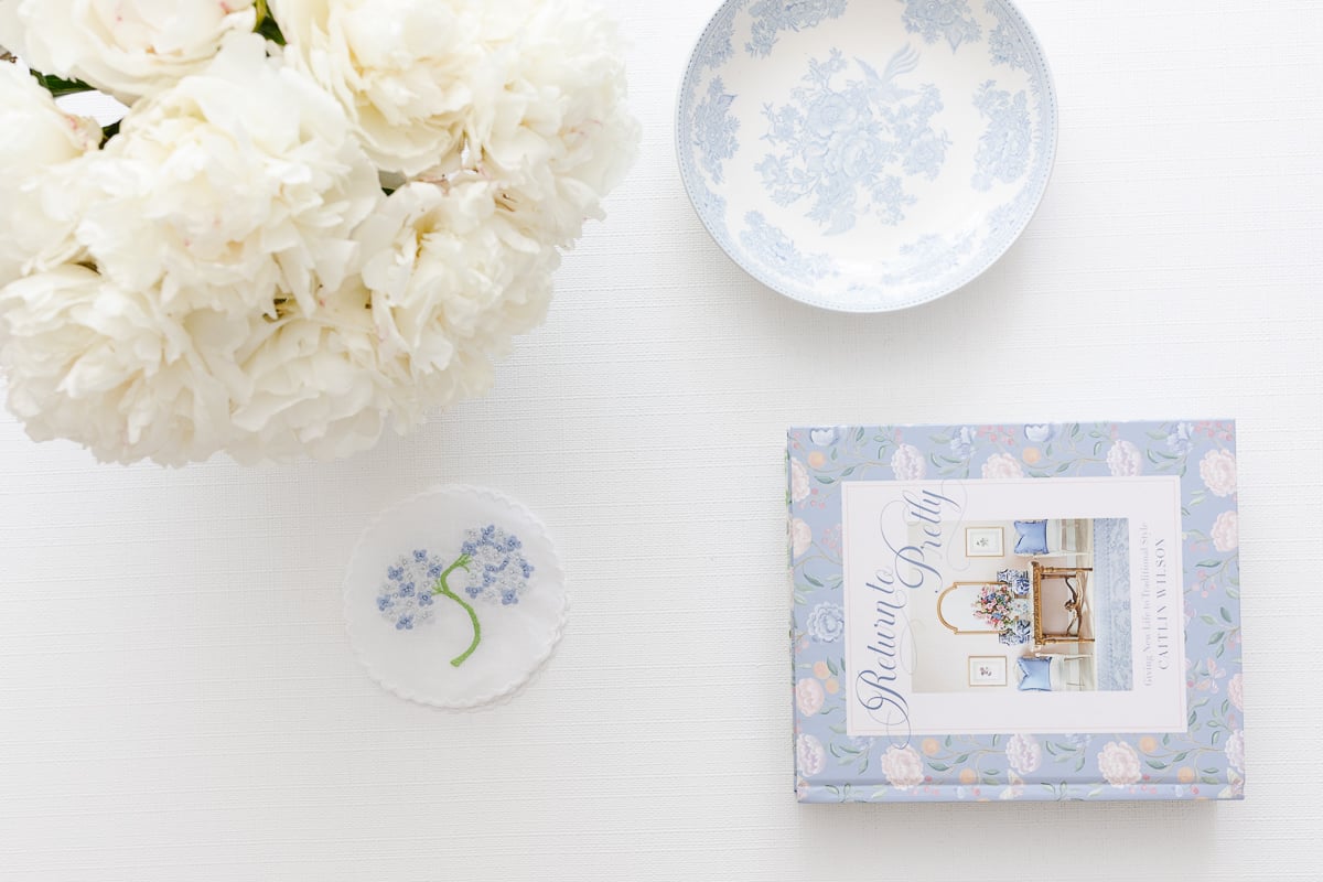 A coffee table featuring white flowers and a blue and white coffee table book.