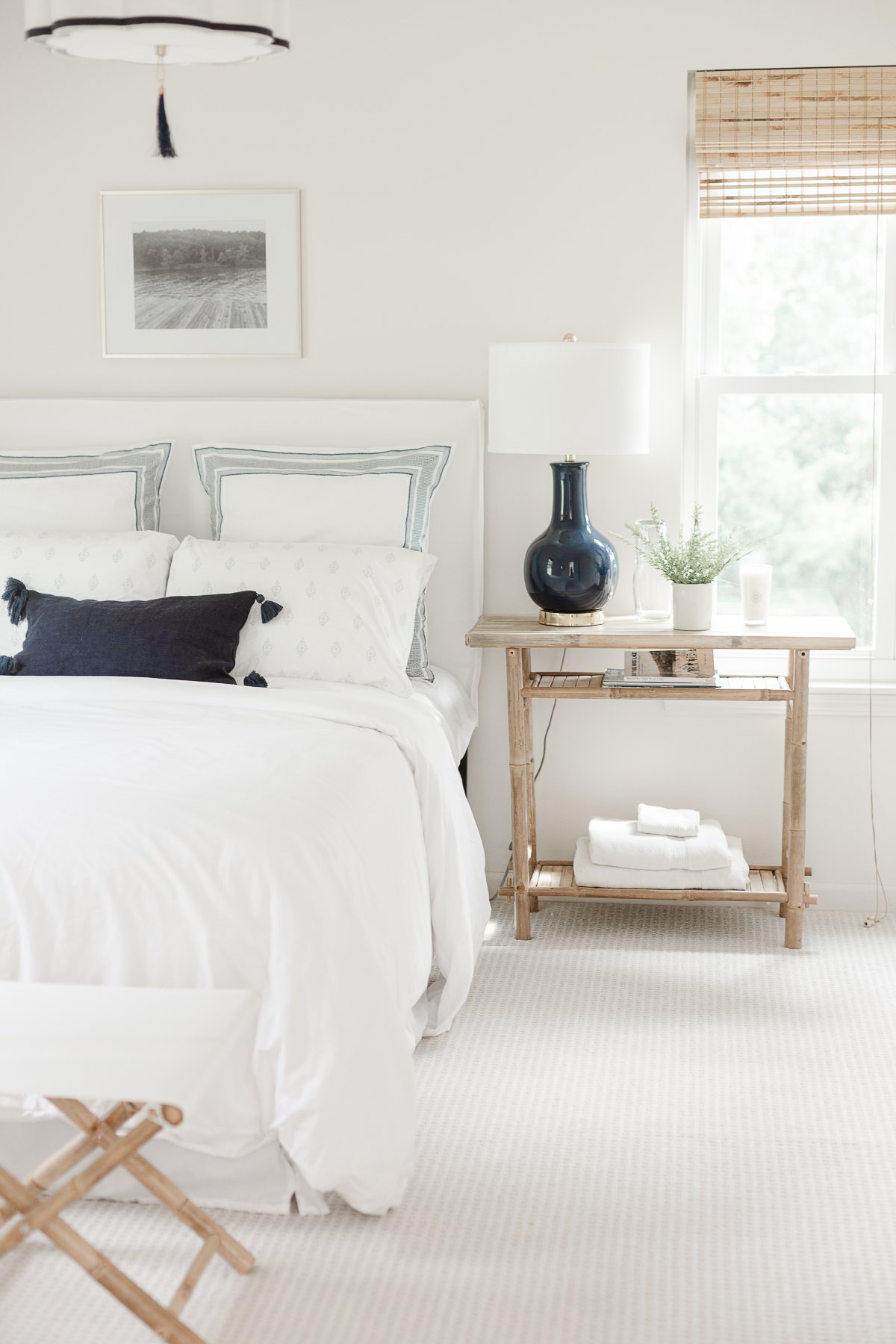 A white bedroom with an upholstered bed and a lamp.