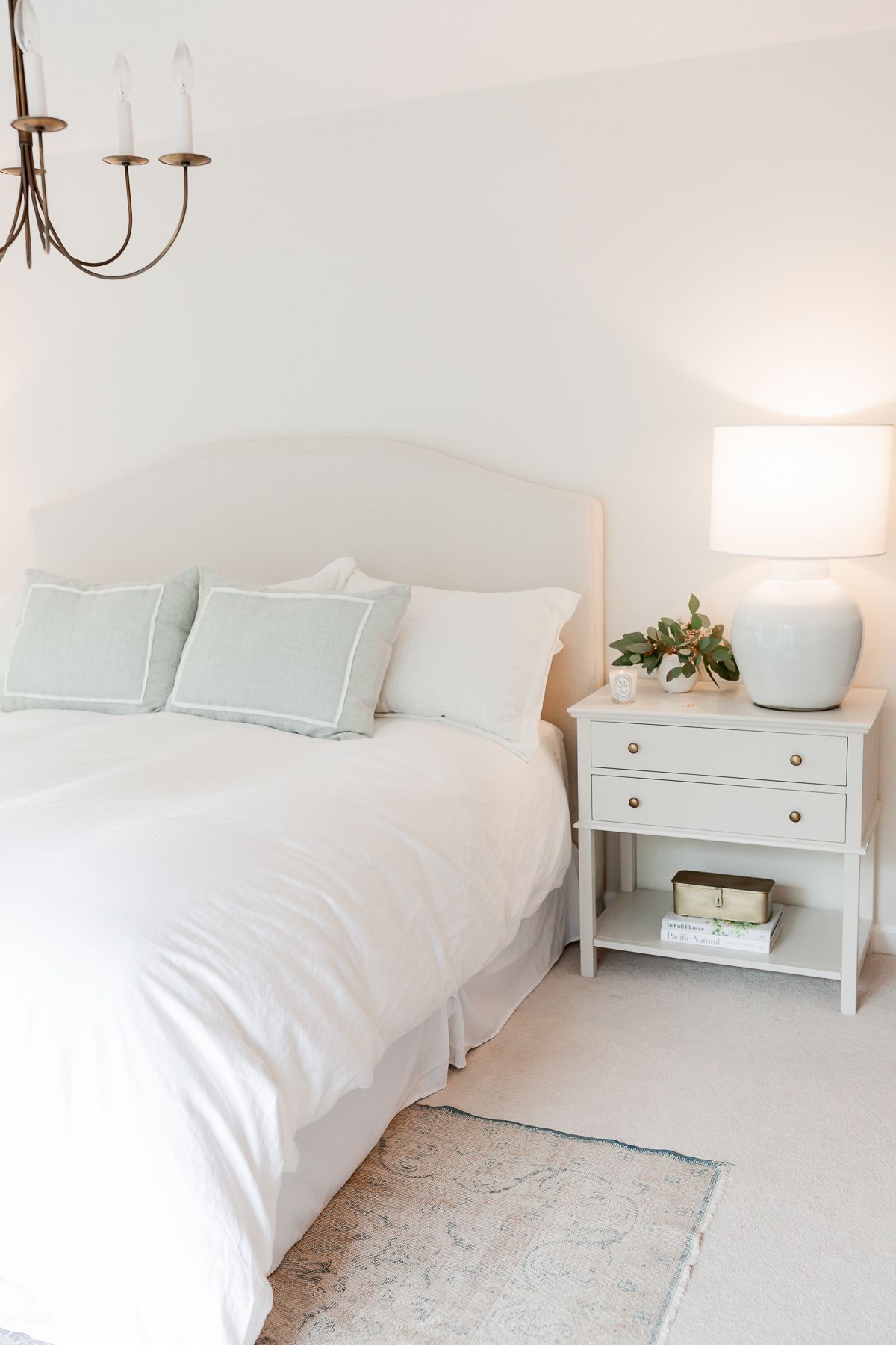 A cream colored bedroom with an upholstered bed