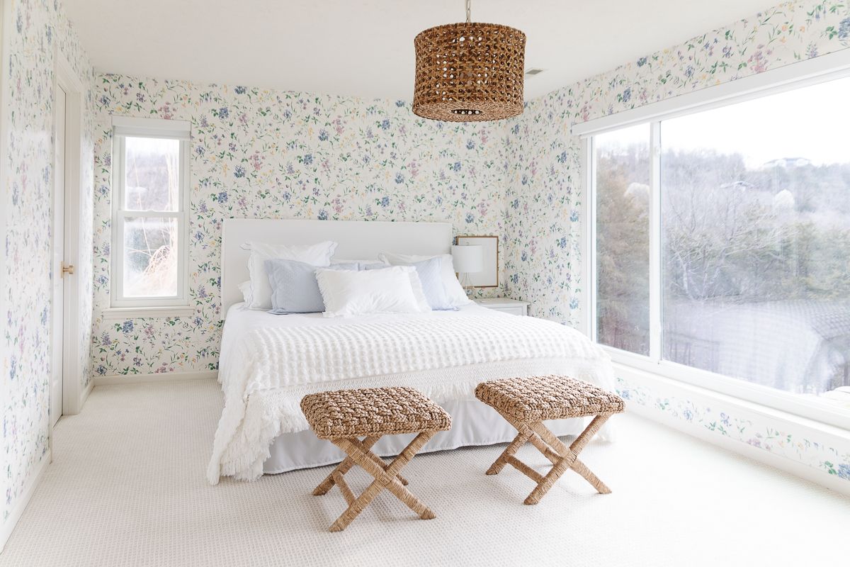 A wallpapered bedroom with a white upholstered bed