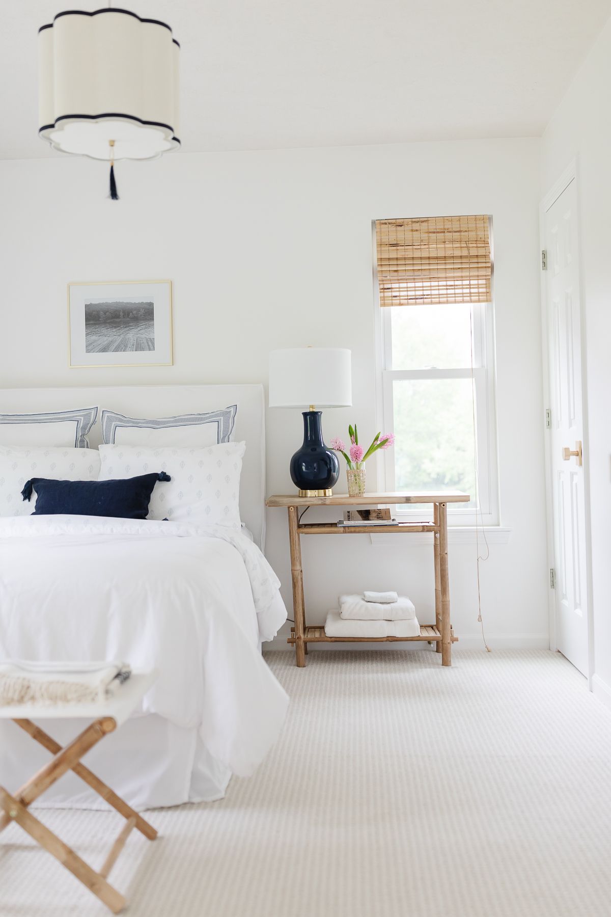 A white bedroom with navy accents and an upholstered bed