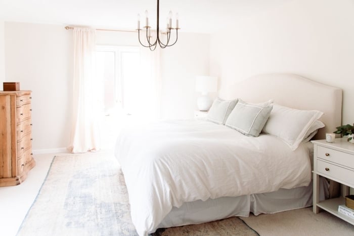 A cream colored bedroom with an upholstered bed