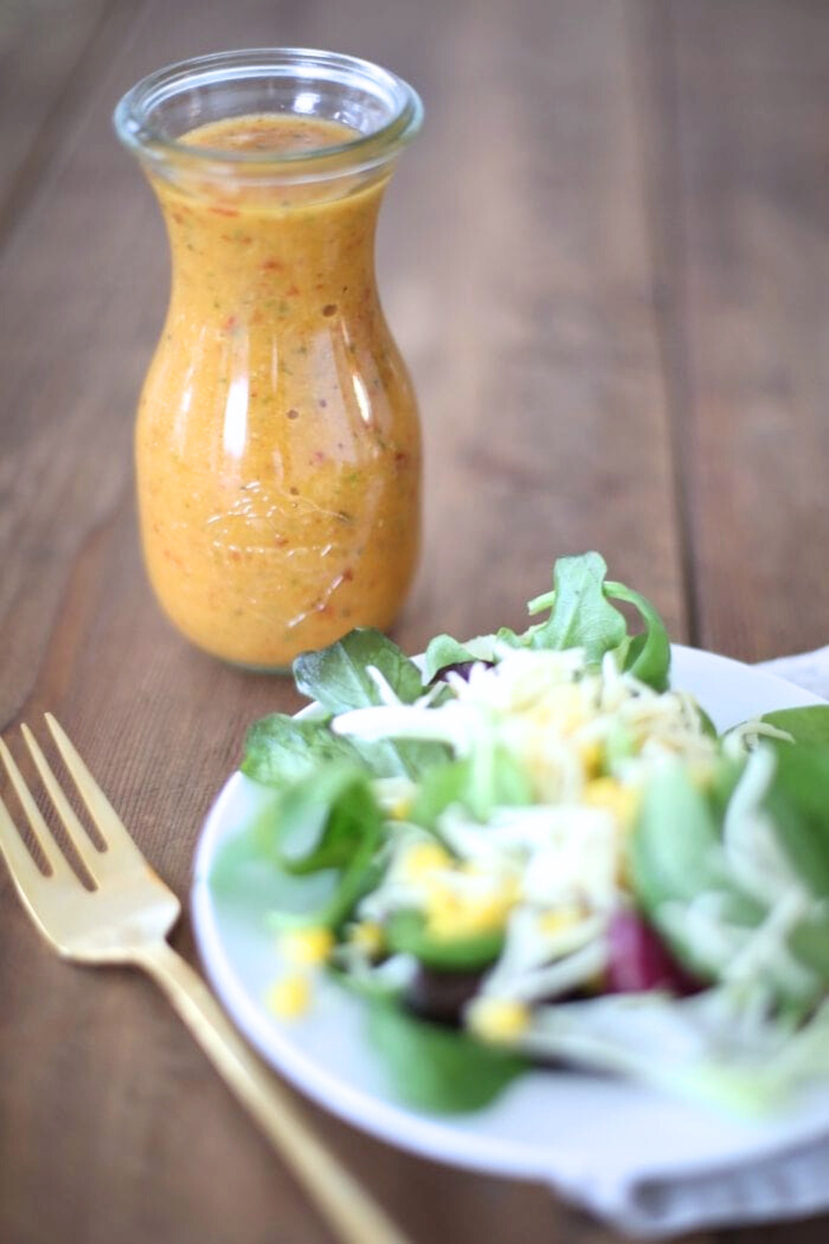 A plate with a salad and a jar of apple dressing.