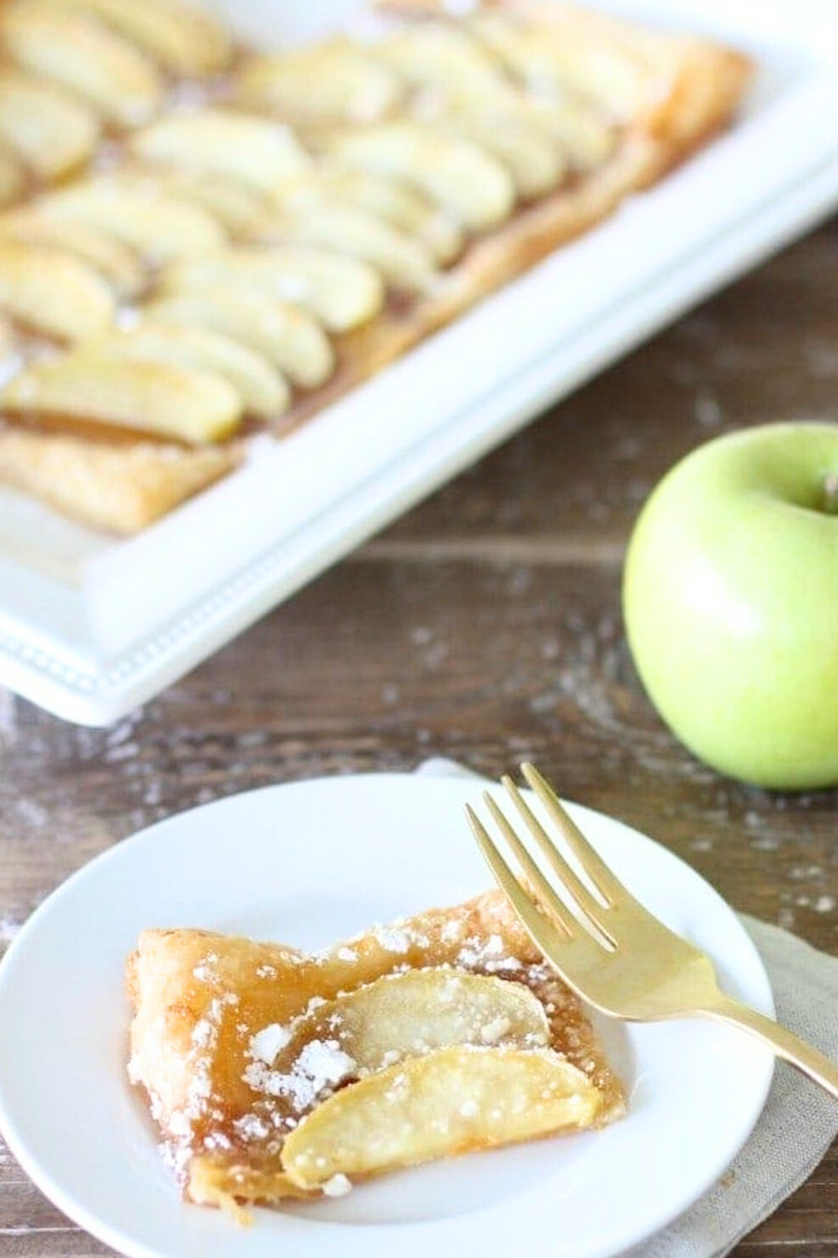 A slice of apple tart 
with powdered sugar on a plate, perfect for apple recipes.