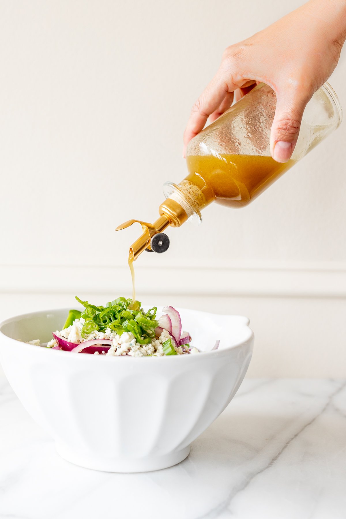 A person pouring a apple dressing into a bowl for their salad recipe.