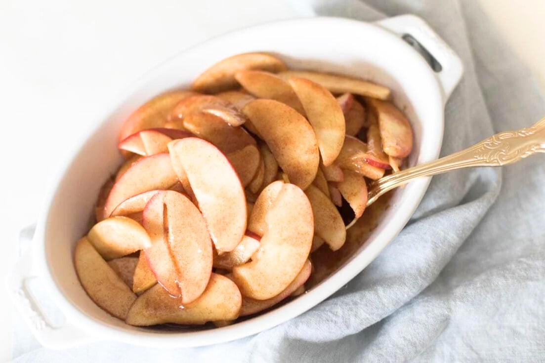 Apple recipes featuring sliced apples in a white bowl with a spoon.