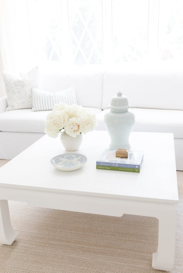 A white coffee table with blue and white coffee table decor.