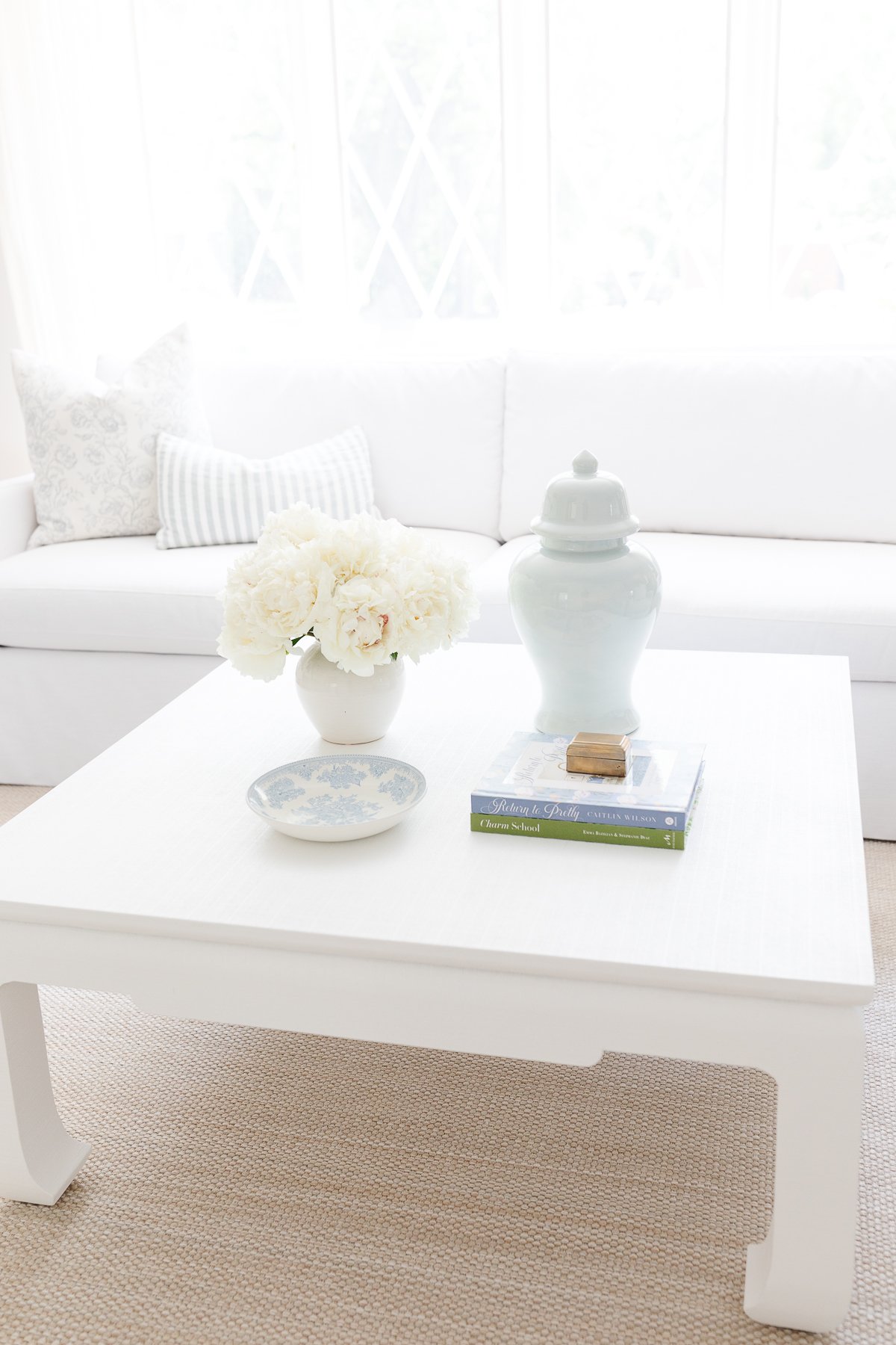 A white coffee table with blue and white coffee table decor.