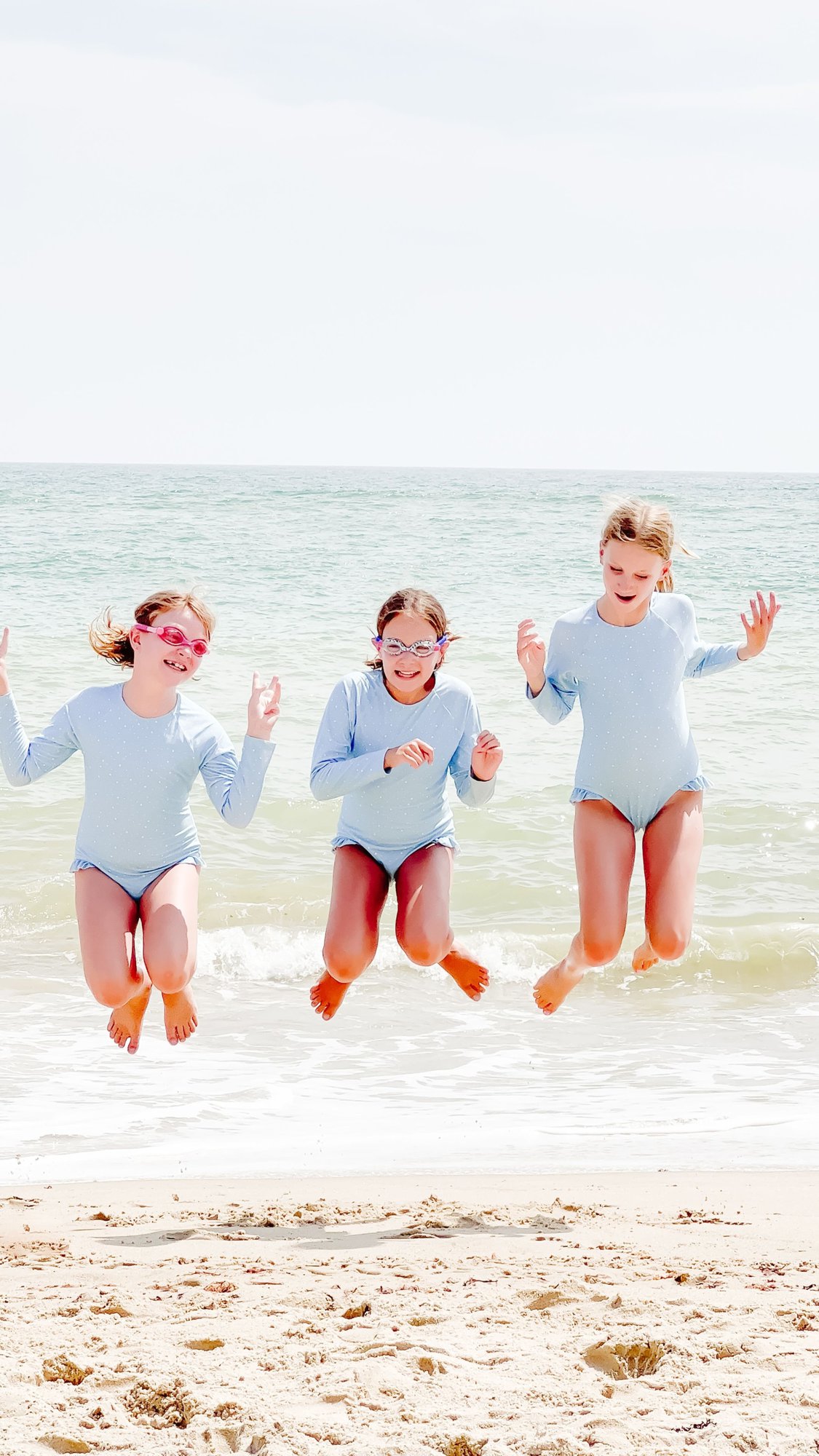 Three little girls jumping for joy on a Martha's Vineyard beach