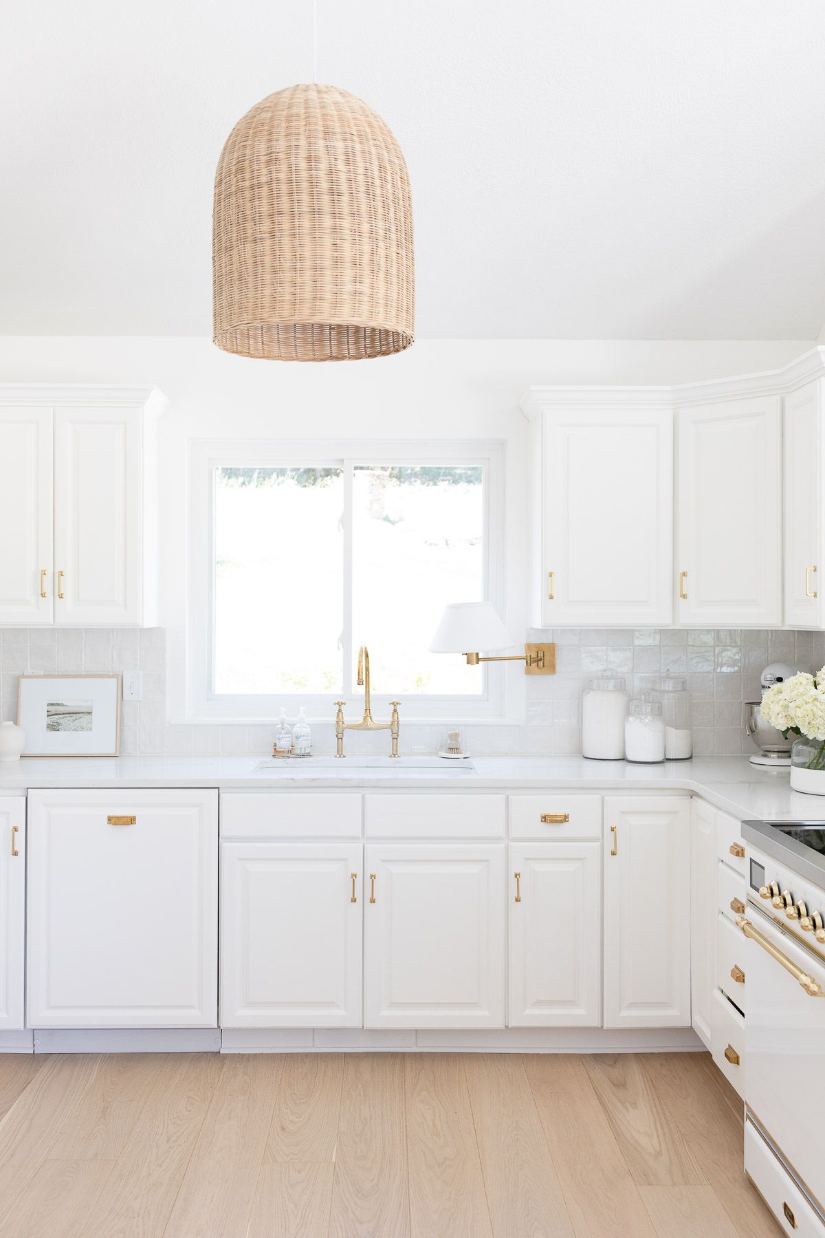 A white kitchen with wood floors, featuring a white induction ILVE Majestic II range