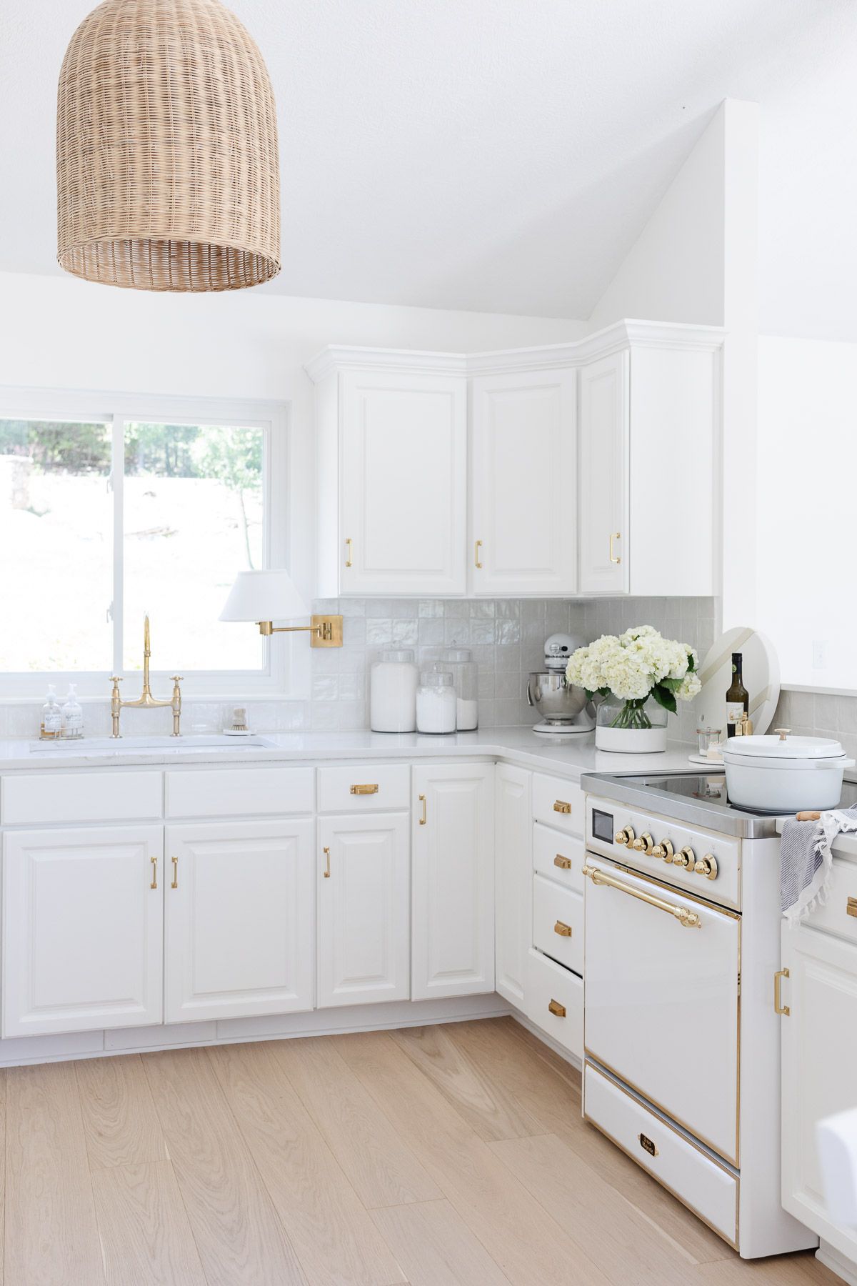 A white kitchen with wood floors, featuring a white ILVE Majestic II range