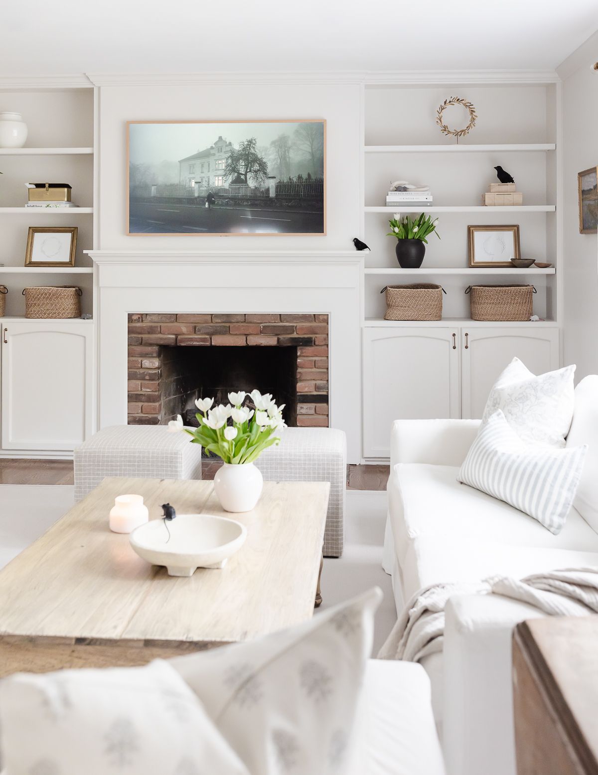 A white living room decorated with Amazon Halloween decor elements, with a spooky scene on the TV over the mantel