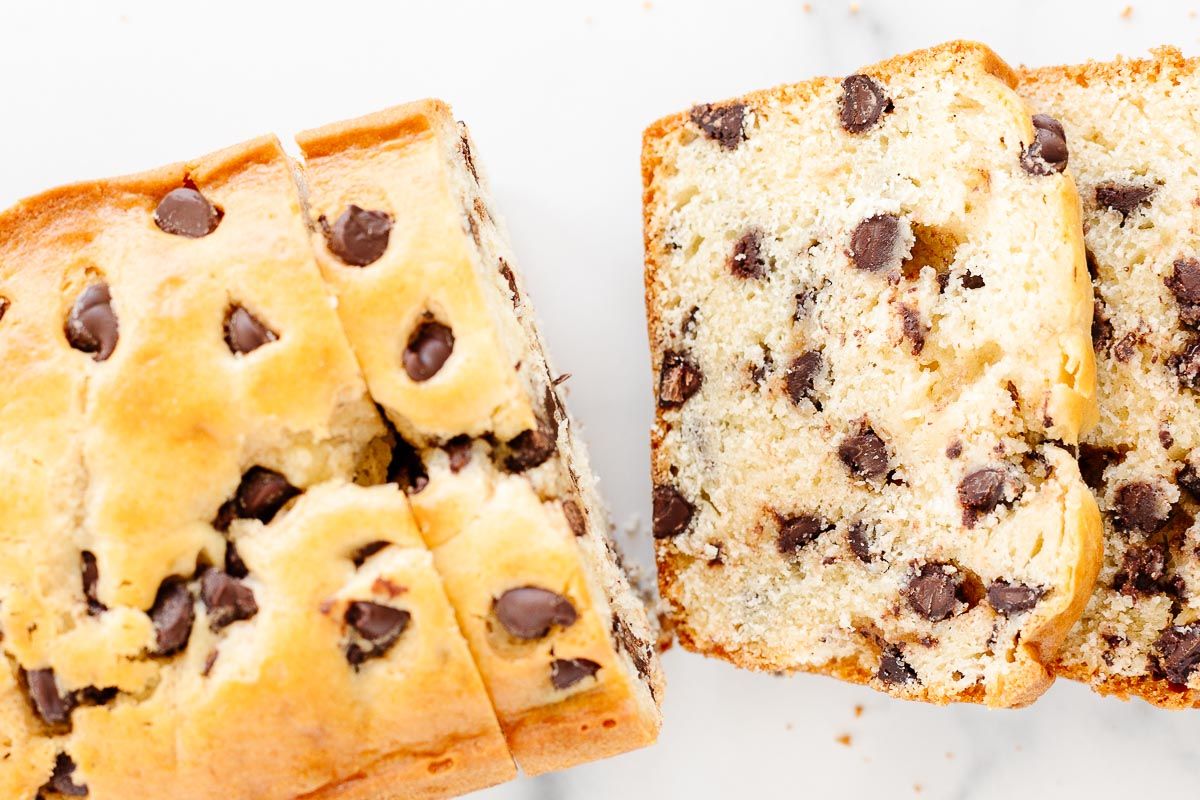 A chocolate chip bread loaf on a marble countertop, sliced for serving.