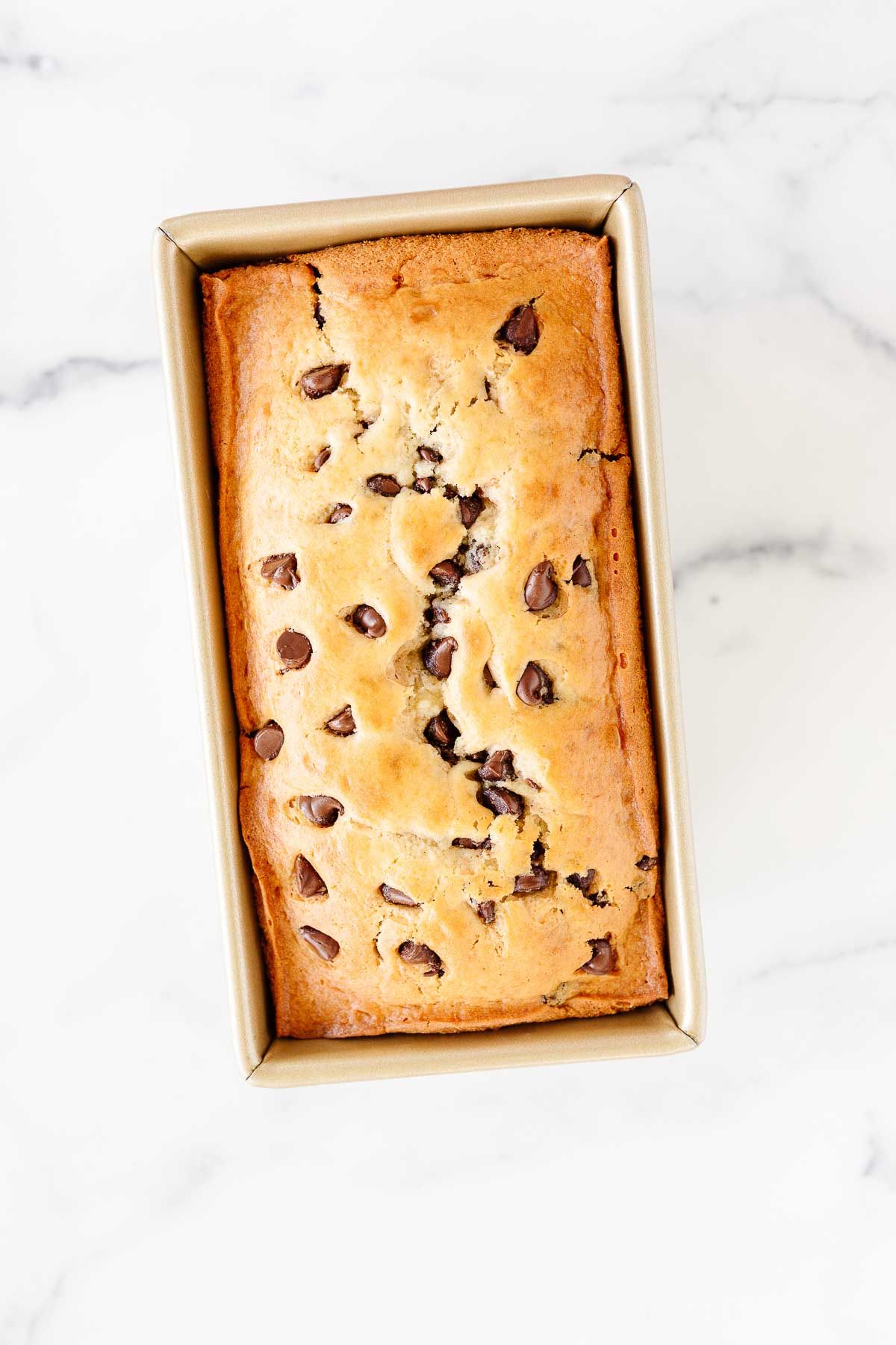 A chocolate chip loaf inside a gold loaf pan.