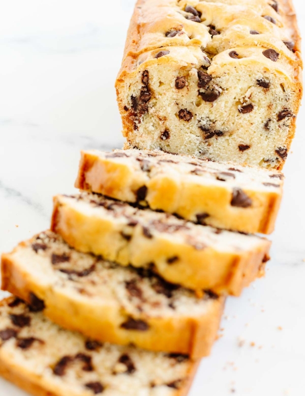 A chocolate chip bread loaf on a marble countertop, sliced for serving.