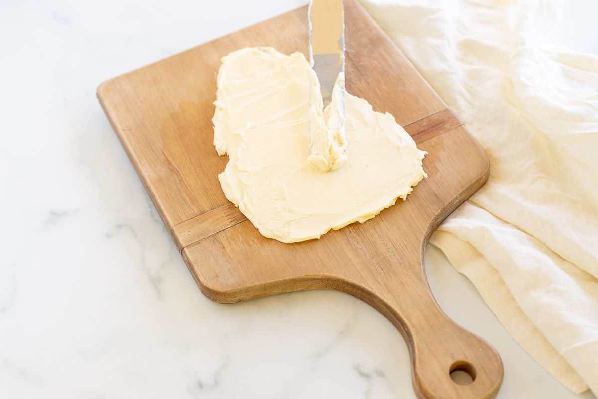 Butter on a wooden serving board, with a knife spreading it into a tree shape