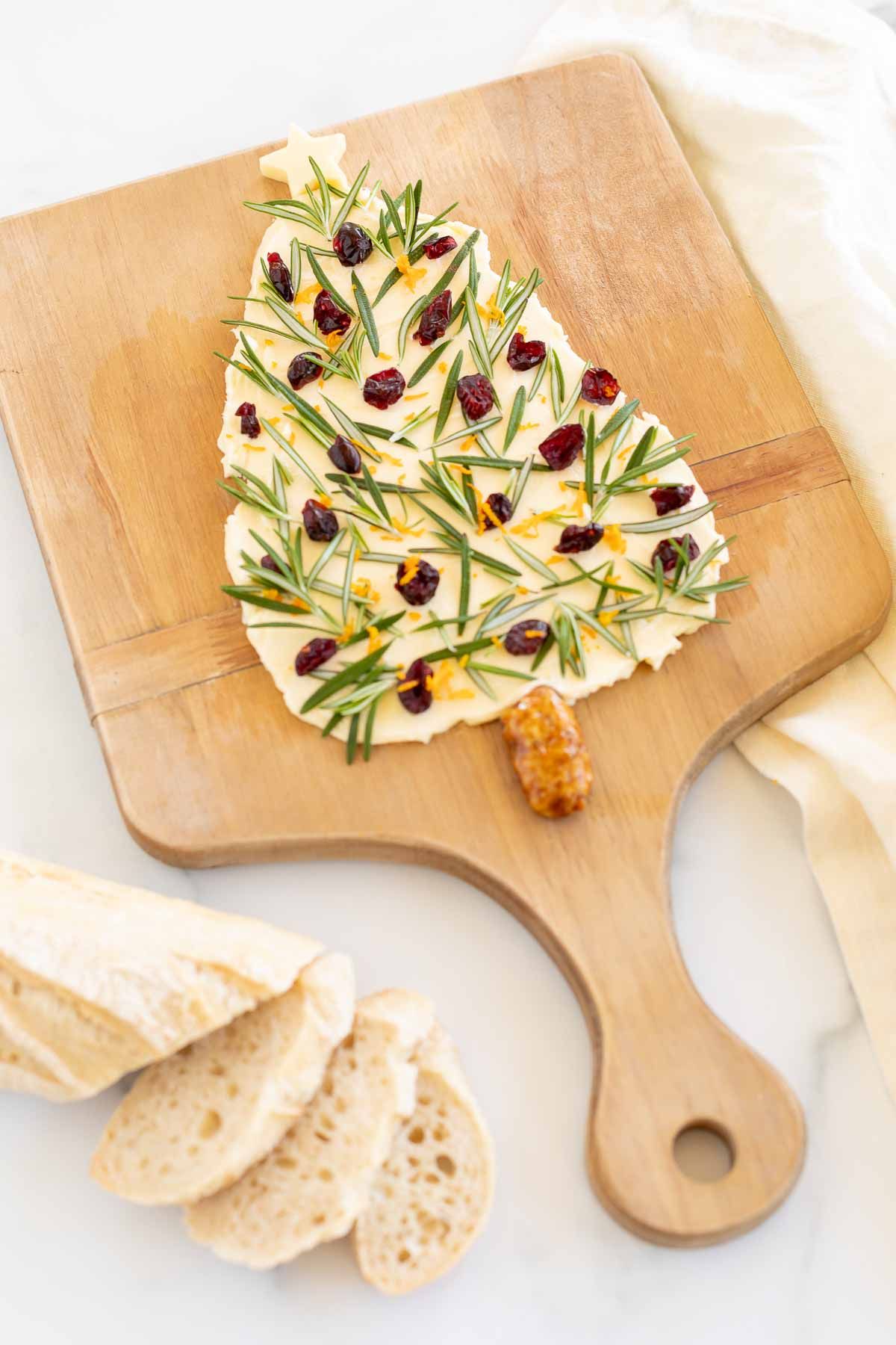 A Christmas butter board, placed on a wooden charcuterie board and shaped into a Christmas tree.