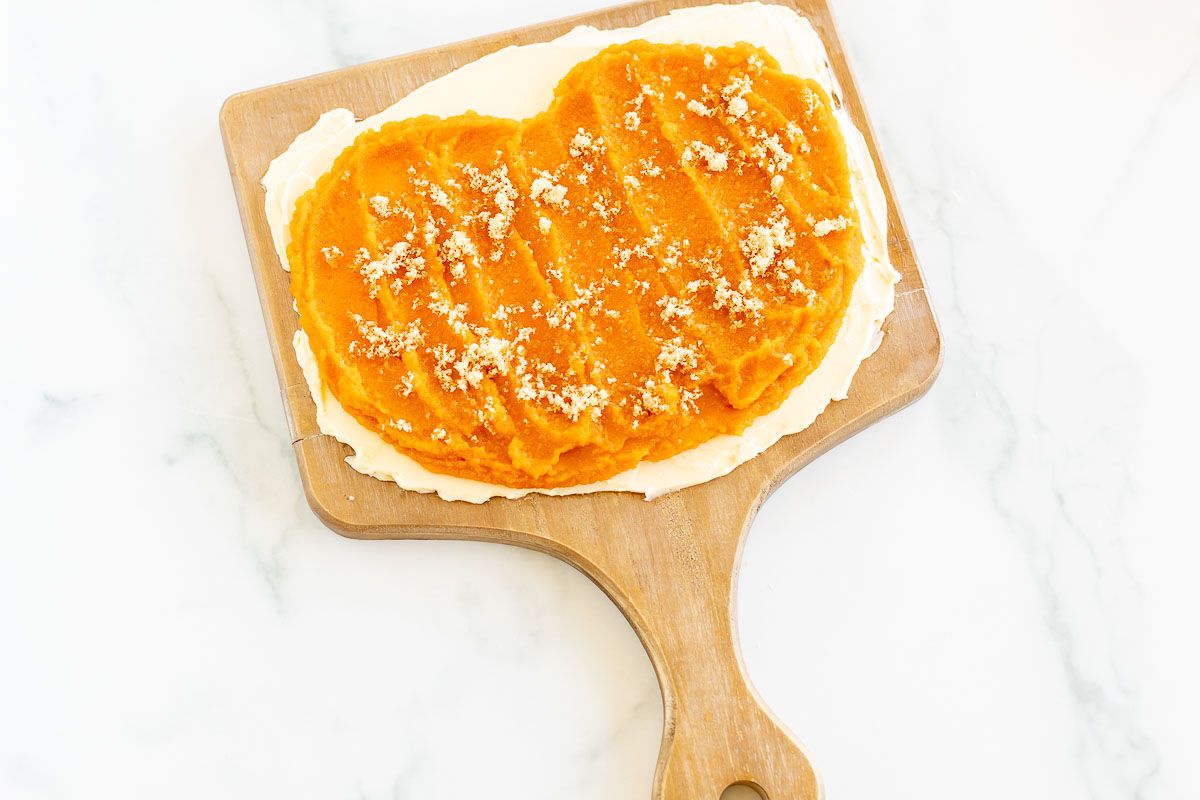 A butter board topped with pumpkin puree, placed on a marble countertop