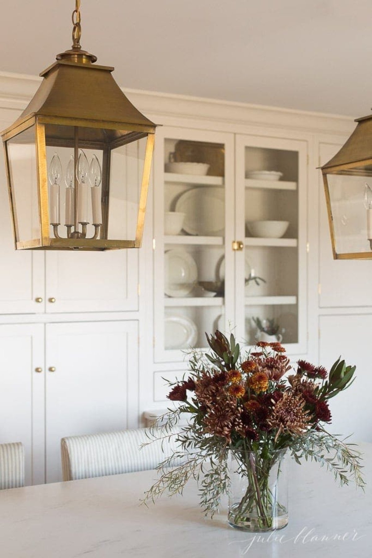 A fall centerpiece with mums on a white marble countertop in a cream kitchen for a fall decorating idea